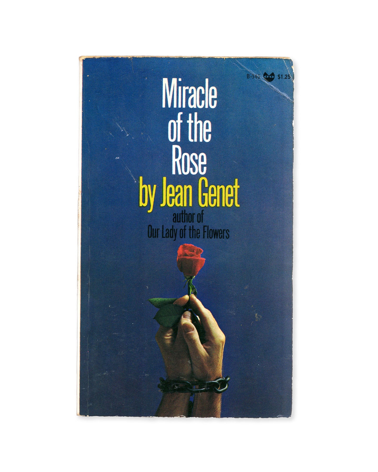 Book cover of 'Miracle of the Rose' by Jean Genet with a hand holding a rose against a blue background.