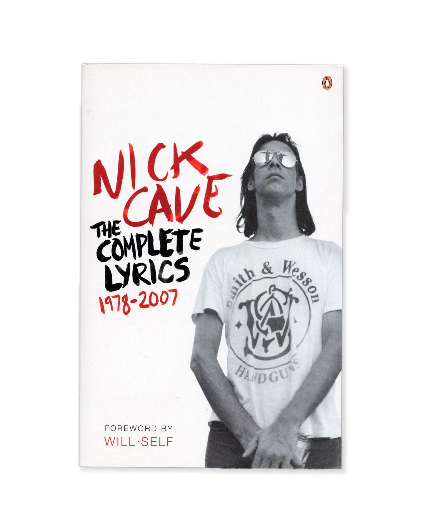 Book cover of 'The Complete Lyrics 1978-2007' by Nick Cave with a photo of Nick Cave wearing a Smith & Wesson tshirt on the cover