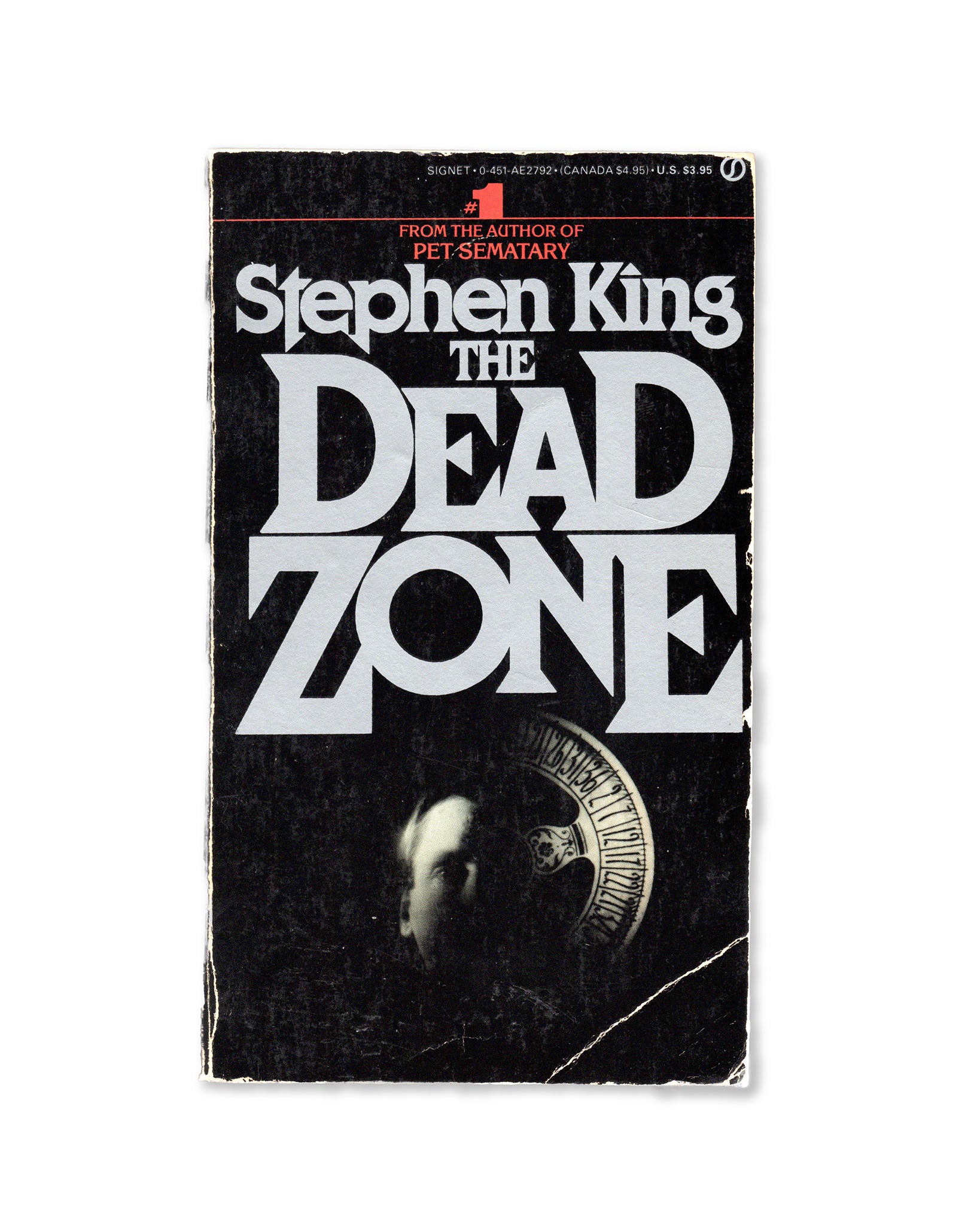 The cover of the paperback book 'The Dead Zone' by Stephen King, featuring a black background with the title in white letters and a image of a skull in the center.